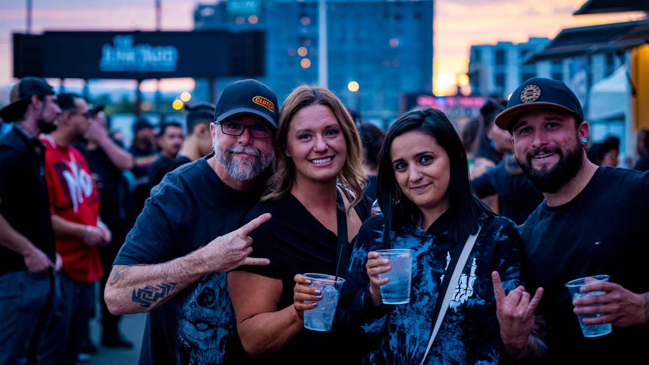 Group of people standing and smiling with drinks in hand.
