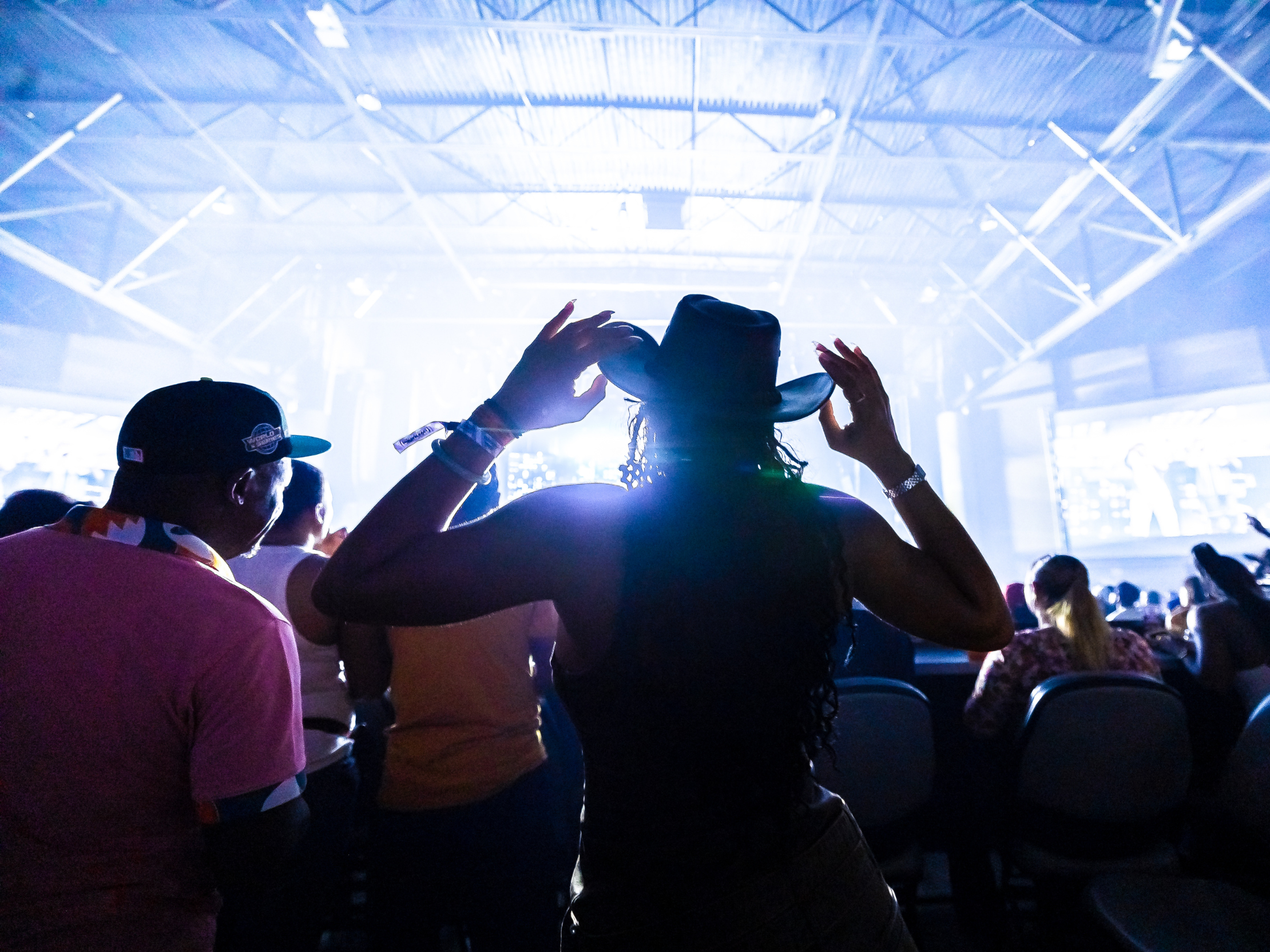 A person wearing a cowboy hat standing and watching a concert