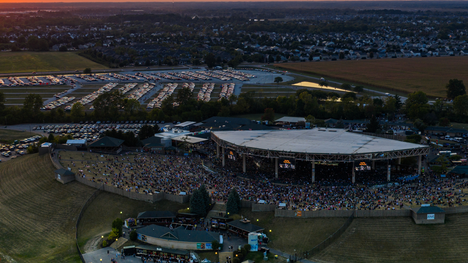 Aerial view of Ruoff Music Center showing the lawn, full venue, and parking lot filled with cars.