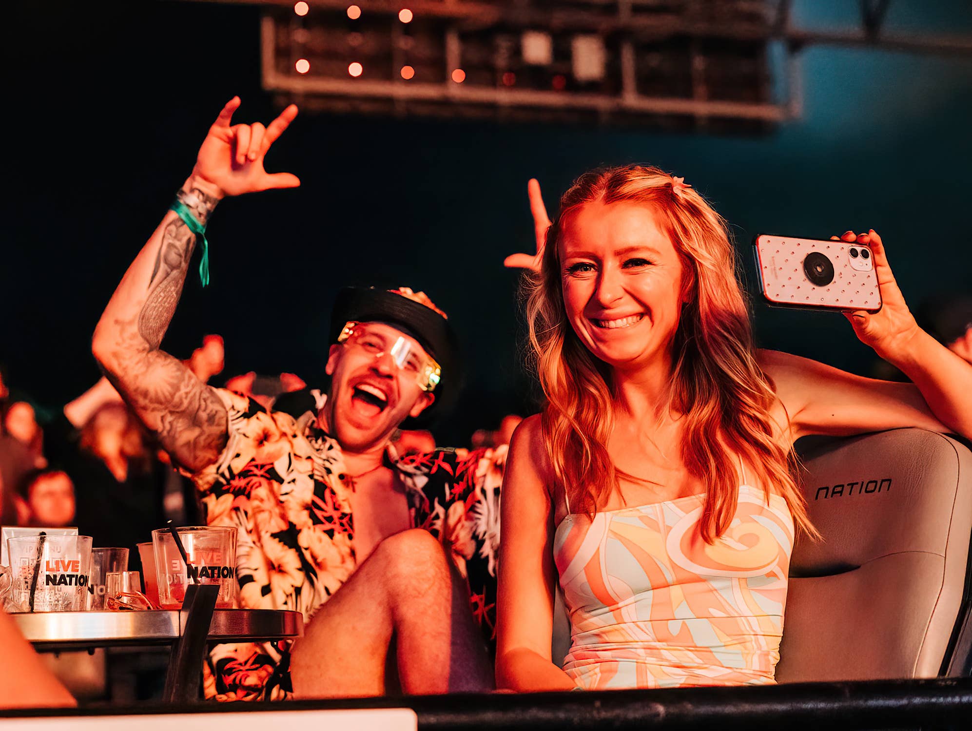 Two fans sitting at a concert smiling and having fun