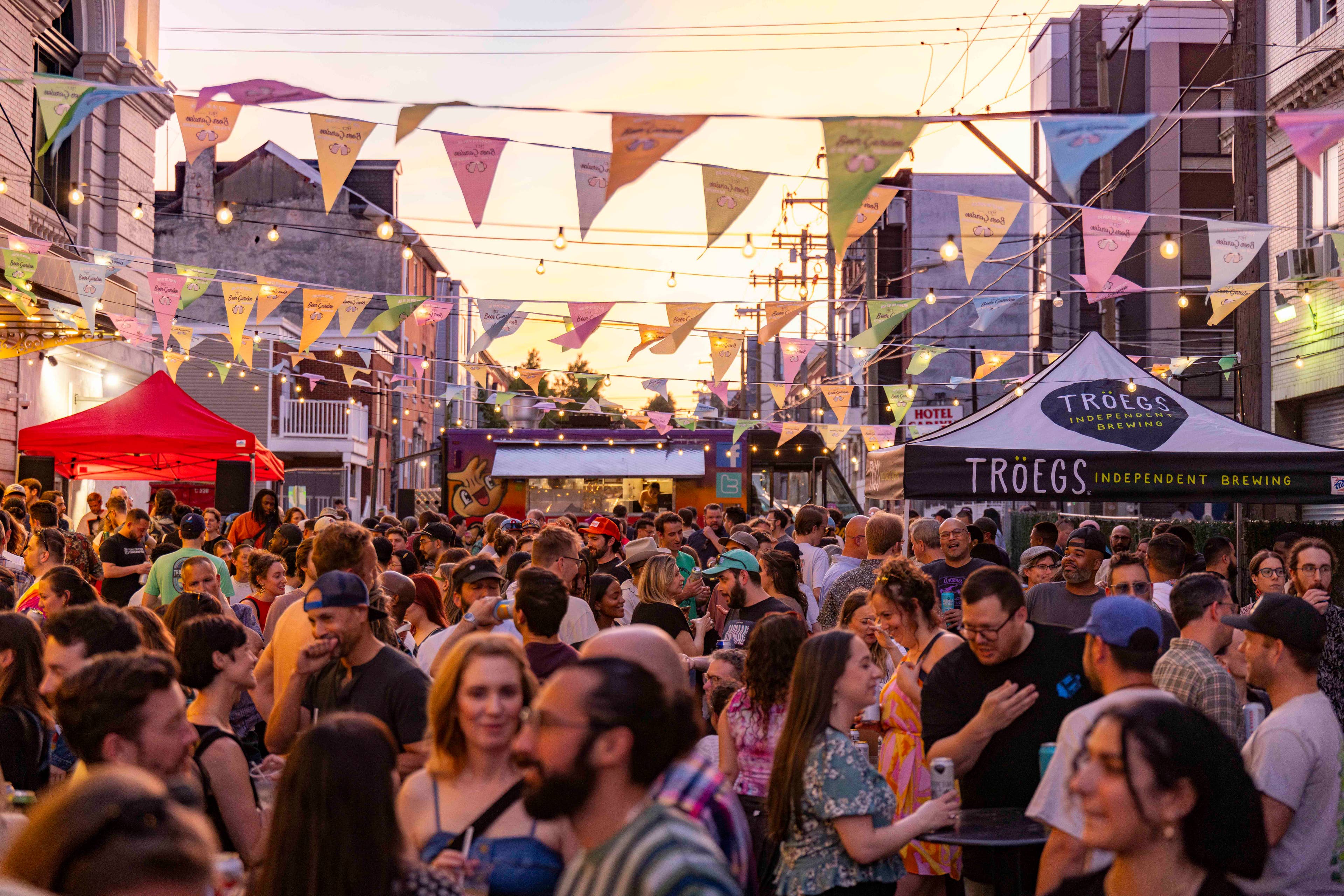 A crowded streets with flags and string lights hung