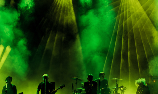 A band playing on stage with green stage lights