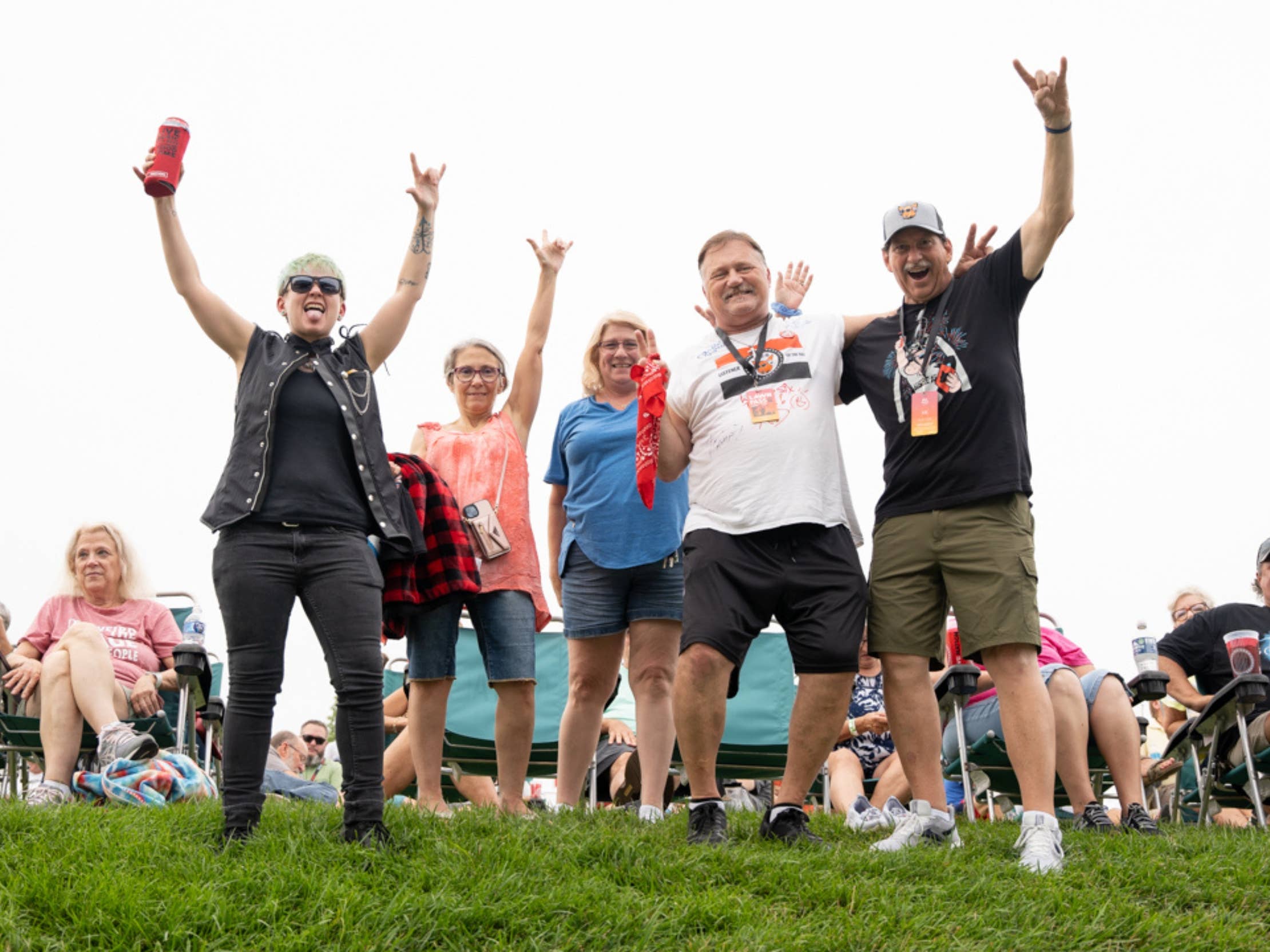 A group of people posing with their hands raised in the air while standing in the lawn.
