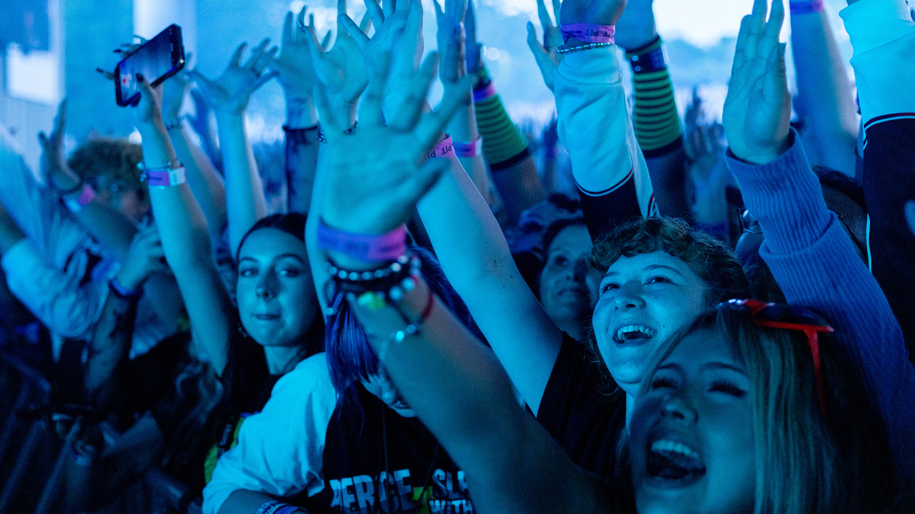 Fans waving in front of rail while Pierce The Veil performs at PNC Music Pavilion.