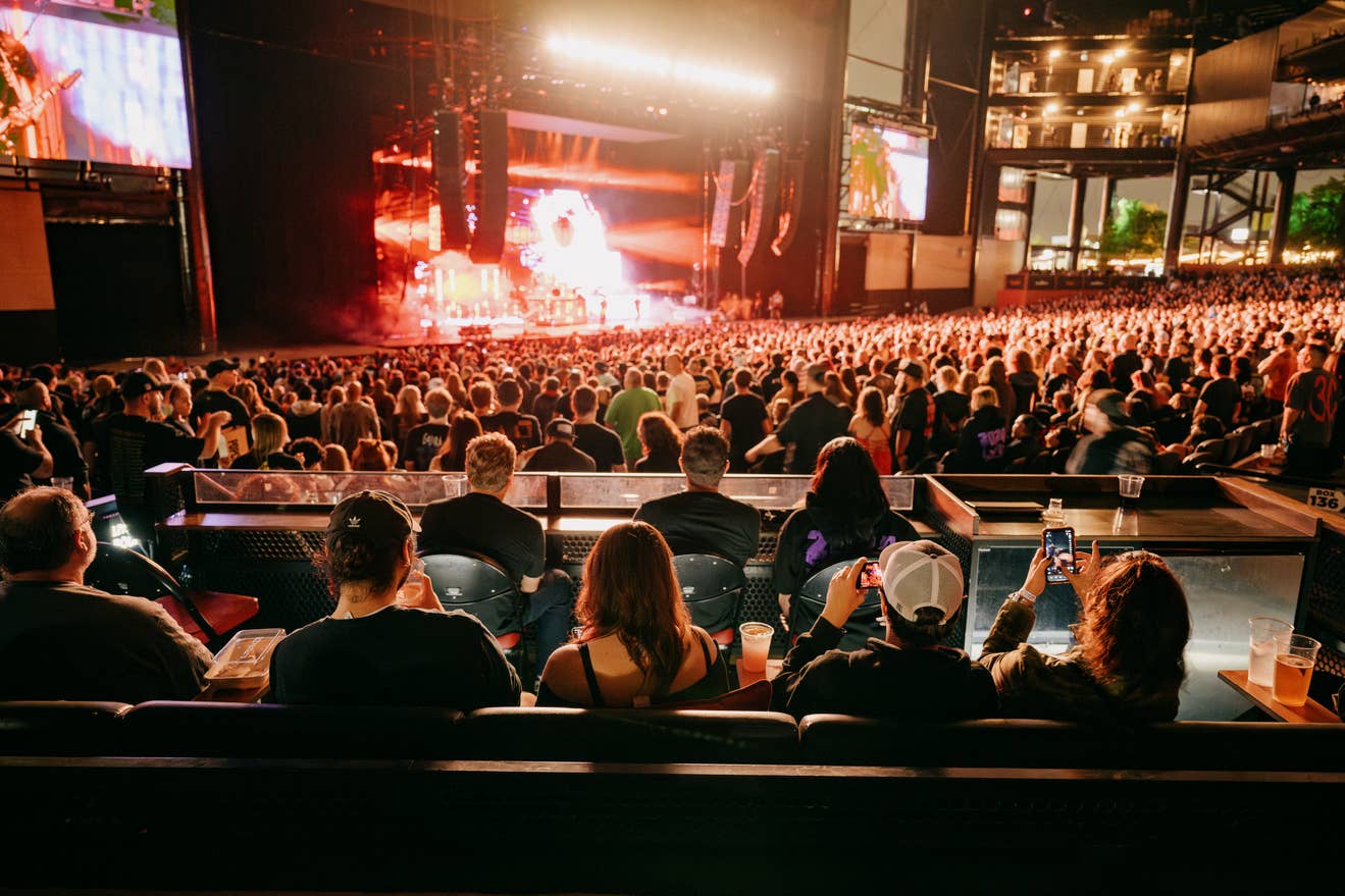 A seated crowd of people looks on as a band performs on stage.