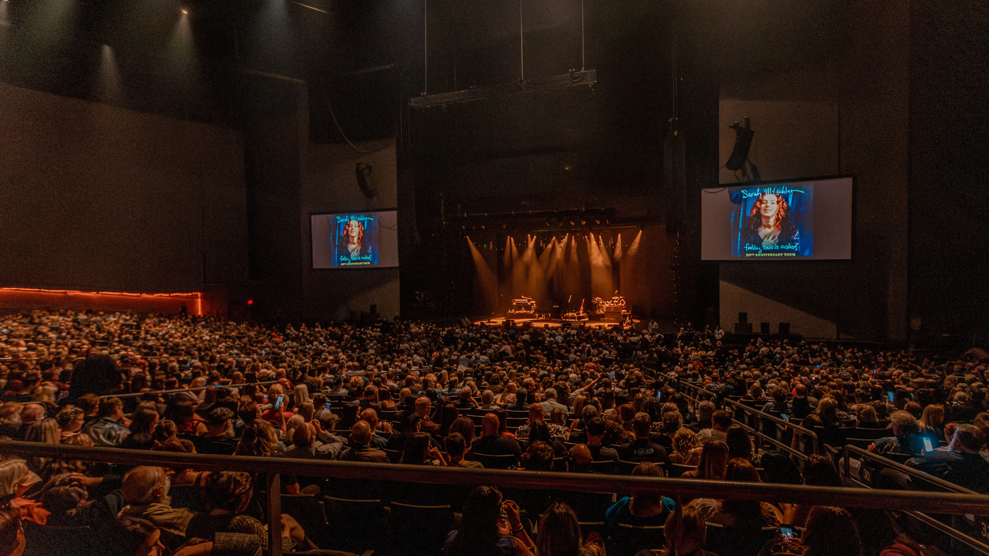 Seats full of fans with the stage lit in the background