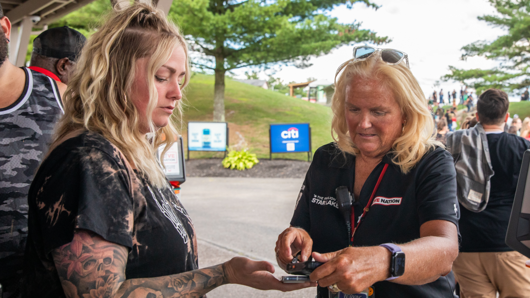 An employee helping scan a fan's mobile ticket to get into the venue.