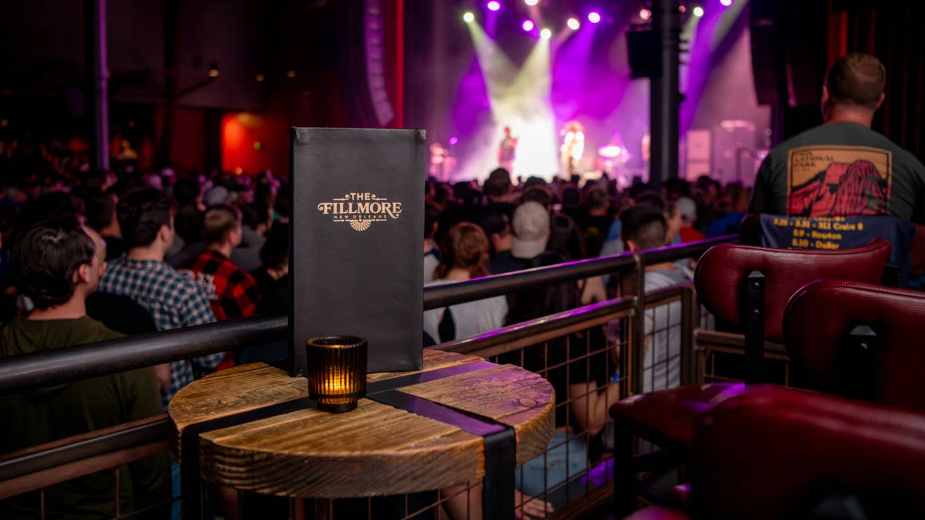 A point of view of a person sitting in the VIP box overlooking a crowd in the standing room facing the stage.