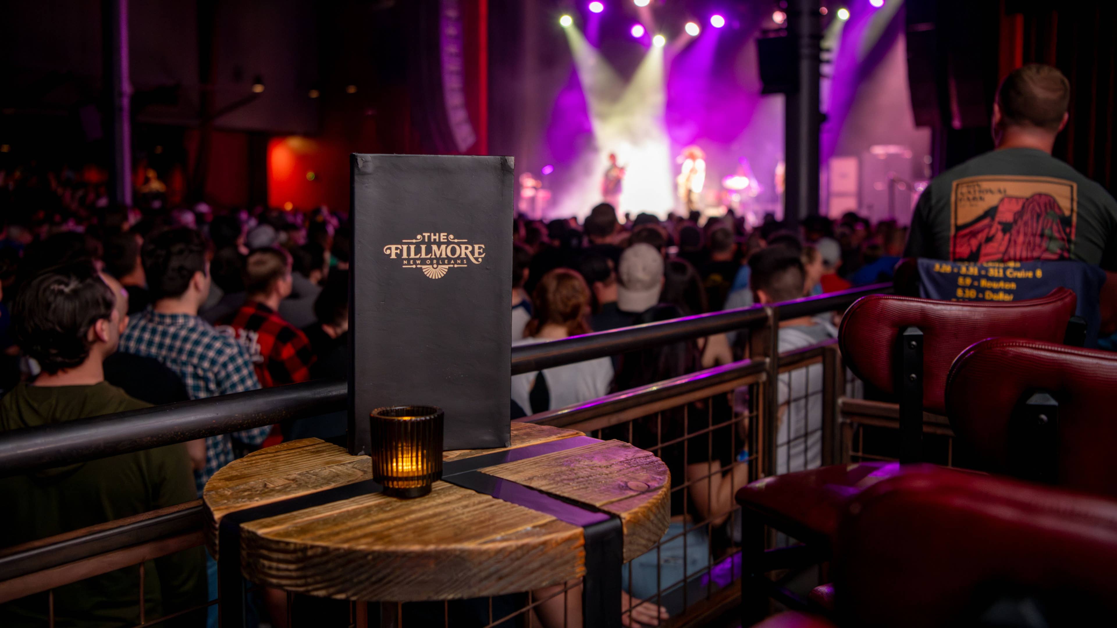 A point of view of a person sitting in the VIP box overlooking a crowd in the standing room facing the stage. 