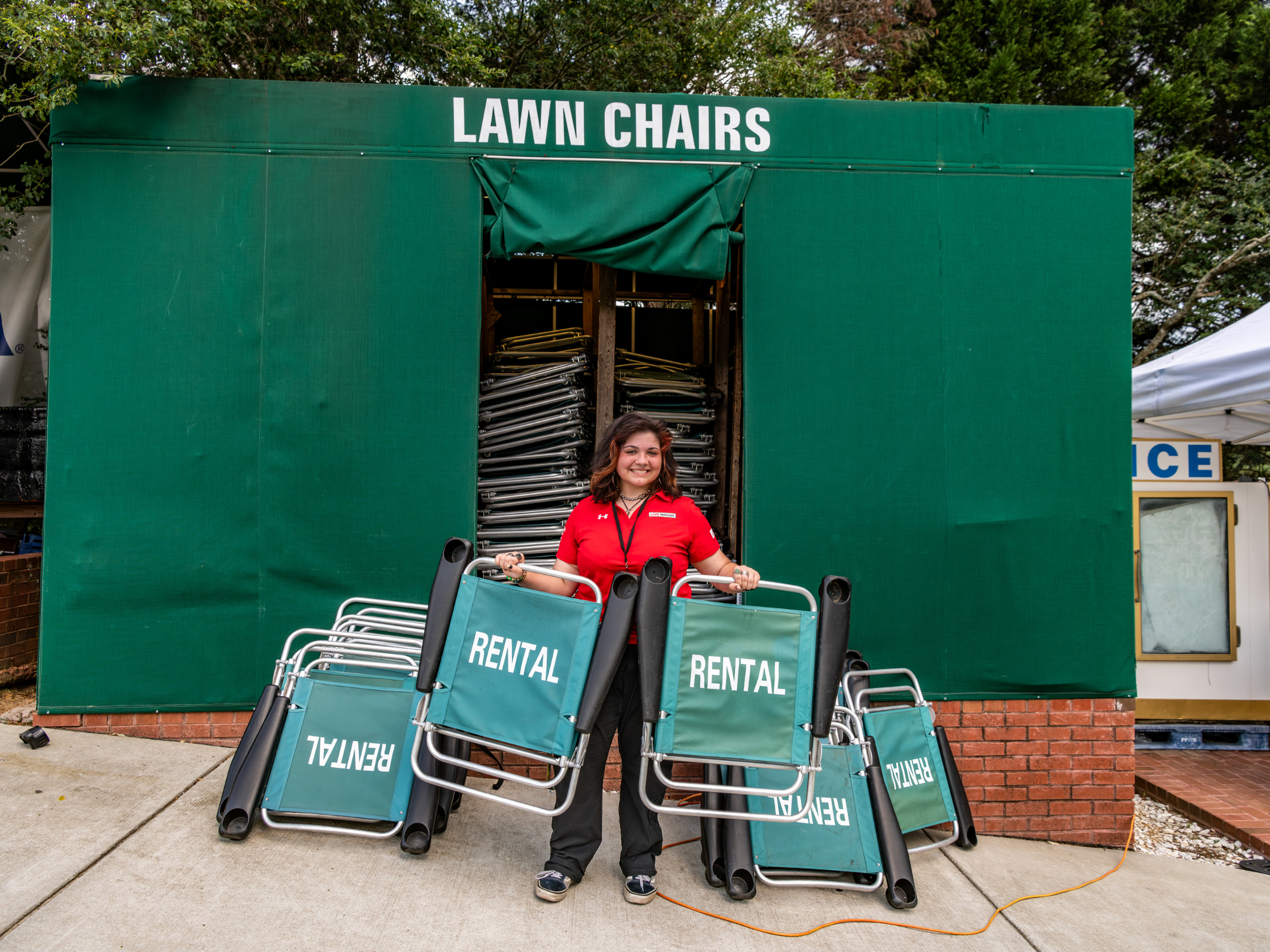 A venue worker holding green lawn chairs
