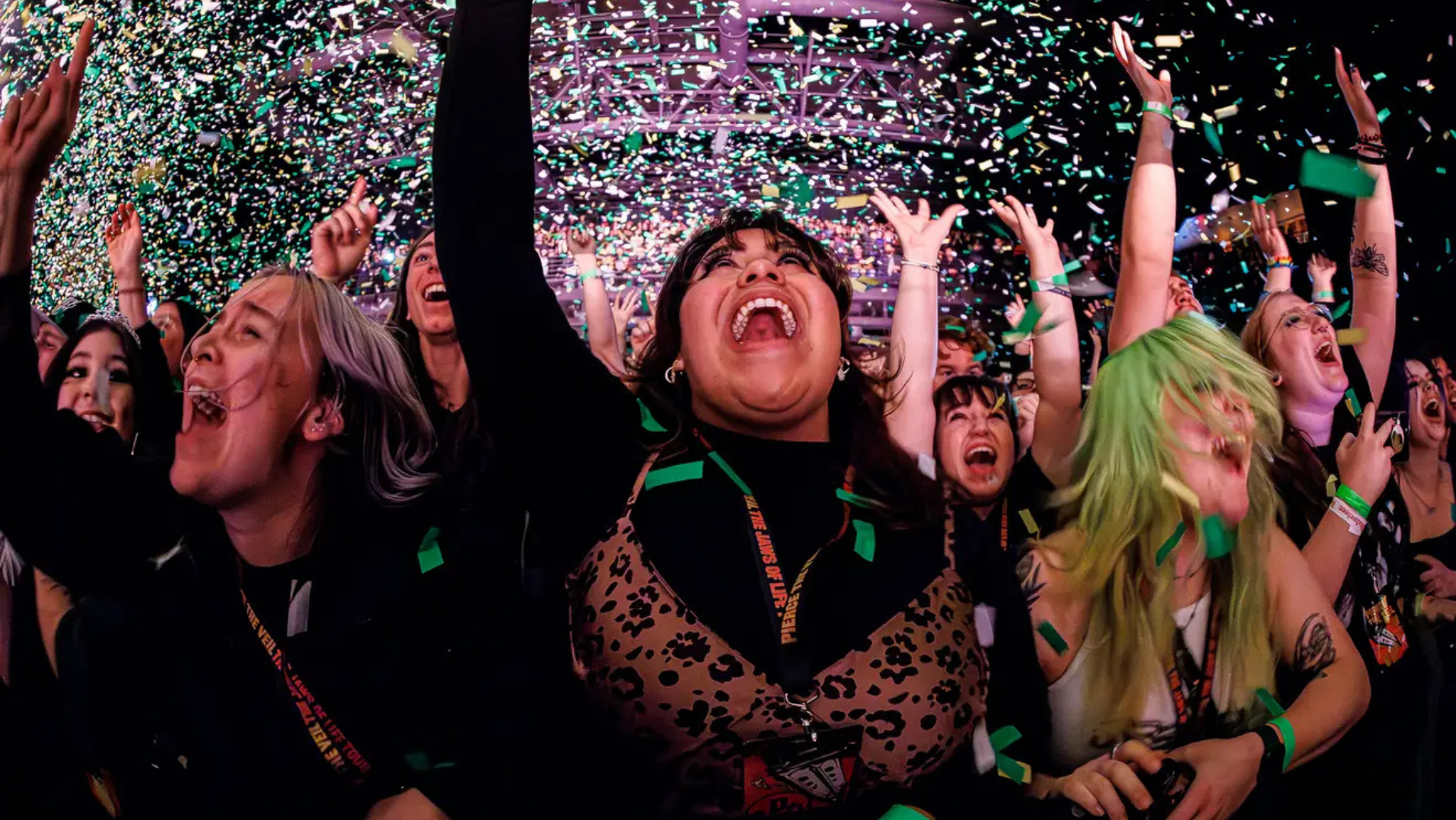 A woman cheering in excitement as confetti drops at a concert.