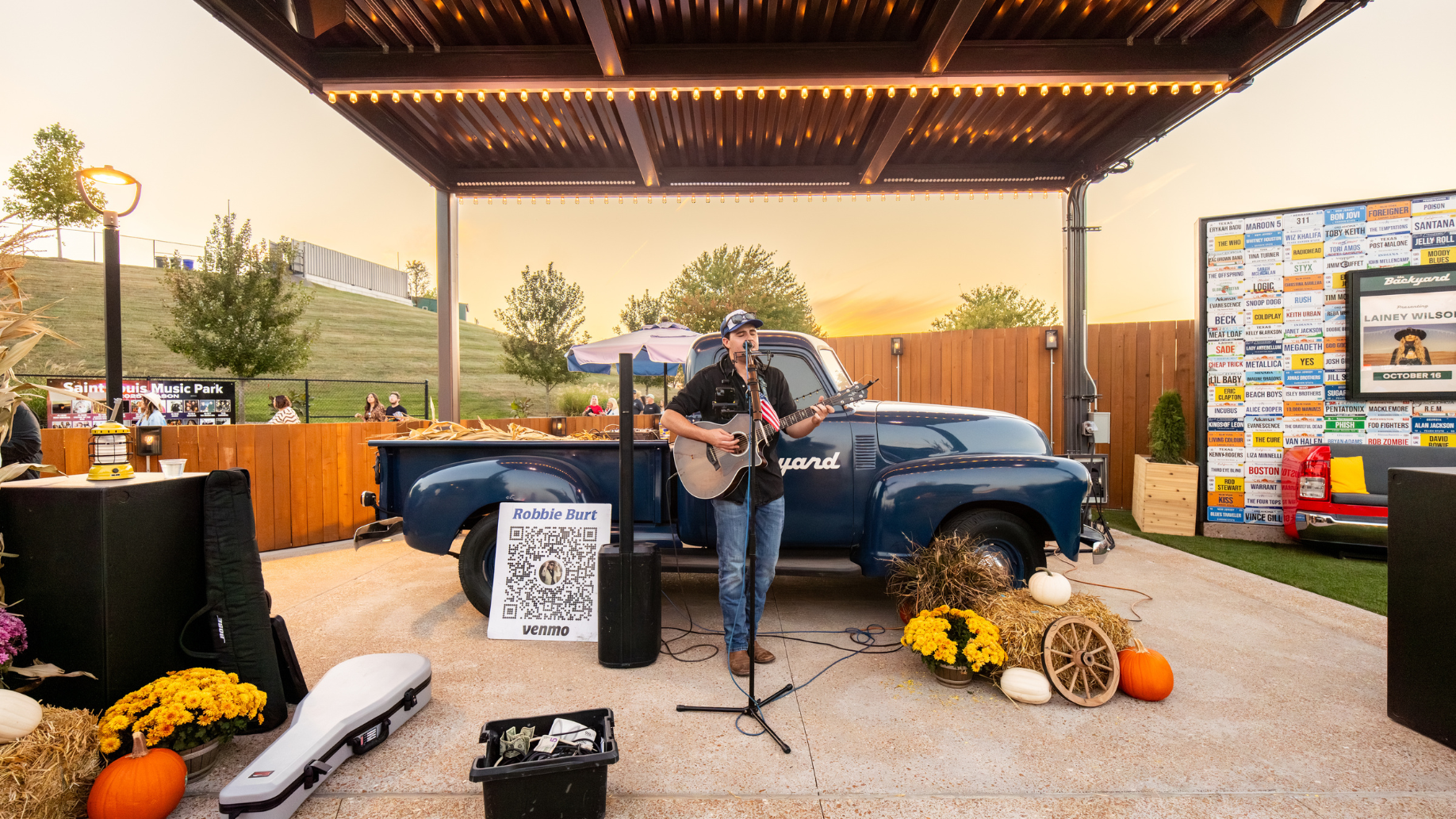 A local artist performs with his guitar in The Backyard VIP Club by the classic Backyard pick-up truck.