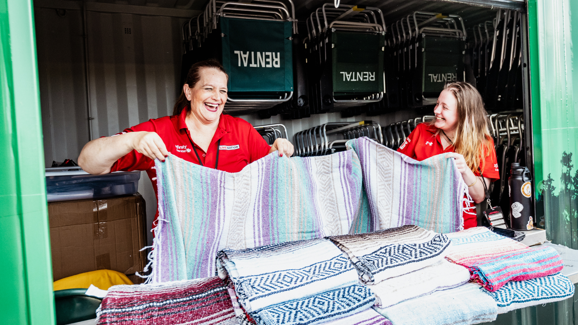 Two employees hold up blankets at the blanket rental stand.