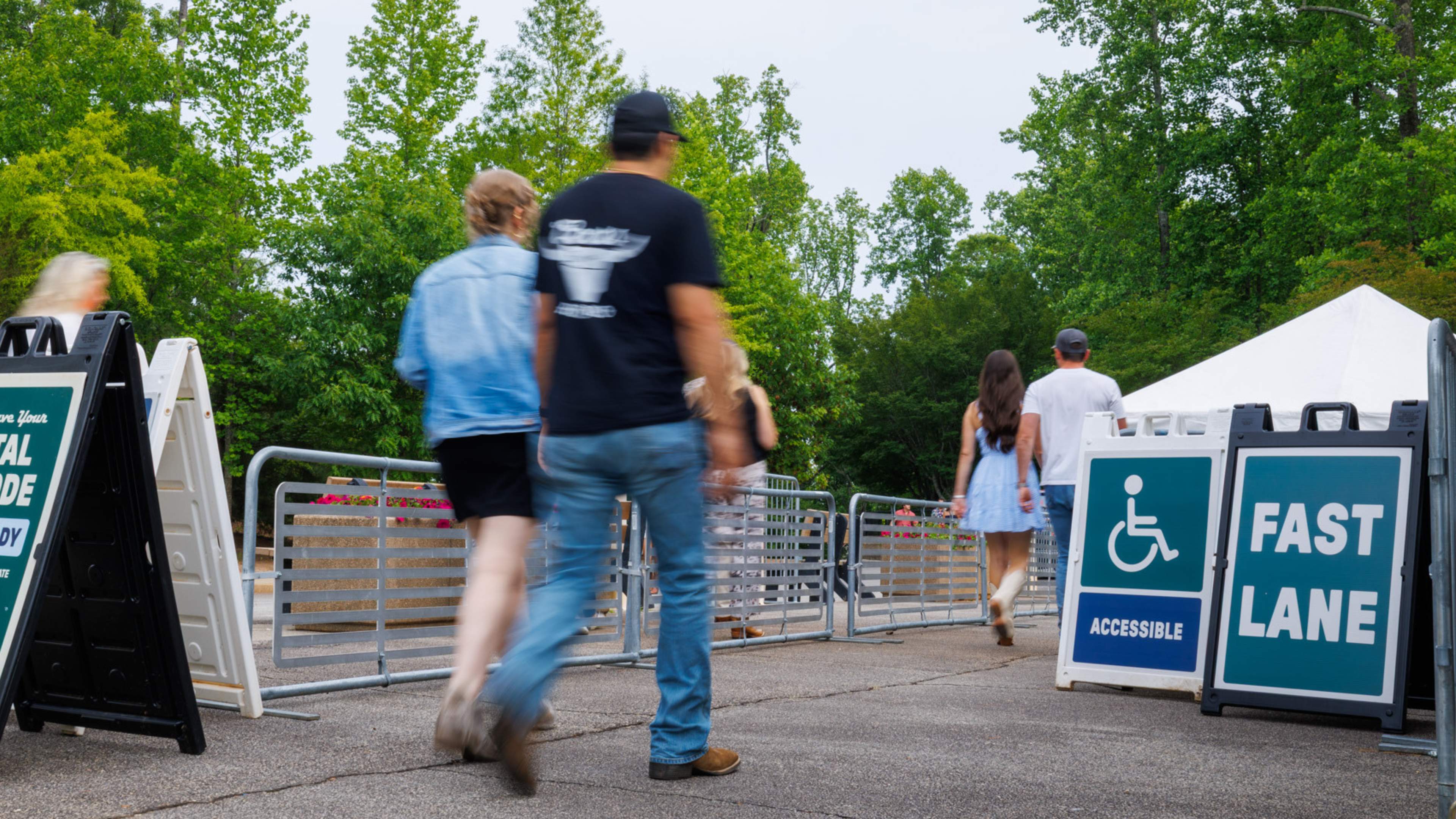 Guests entering a Fast Lane queue outside the venue gates, guided by barricaded lanes and bold “FAST LANE” signage directing them toward a dedicated entrance.