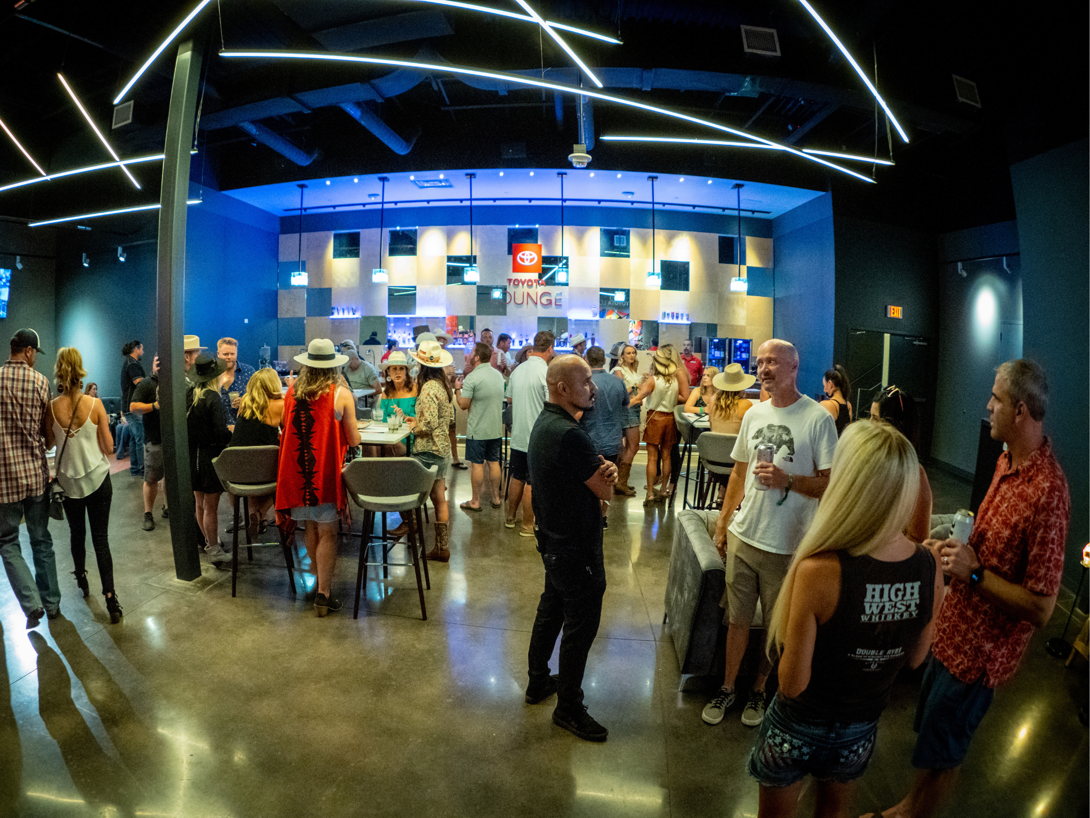 Fans standing throughout the Toyota Lounge, with tables, chairs, and a bar in the background.