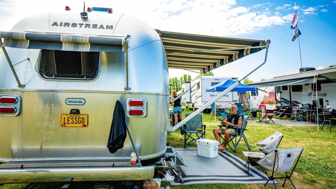 An RV with an awning with camp chairs set up