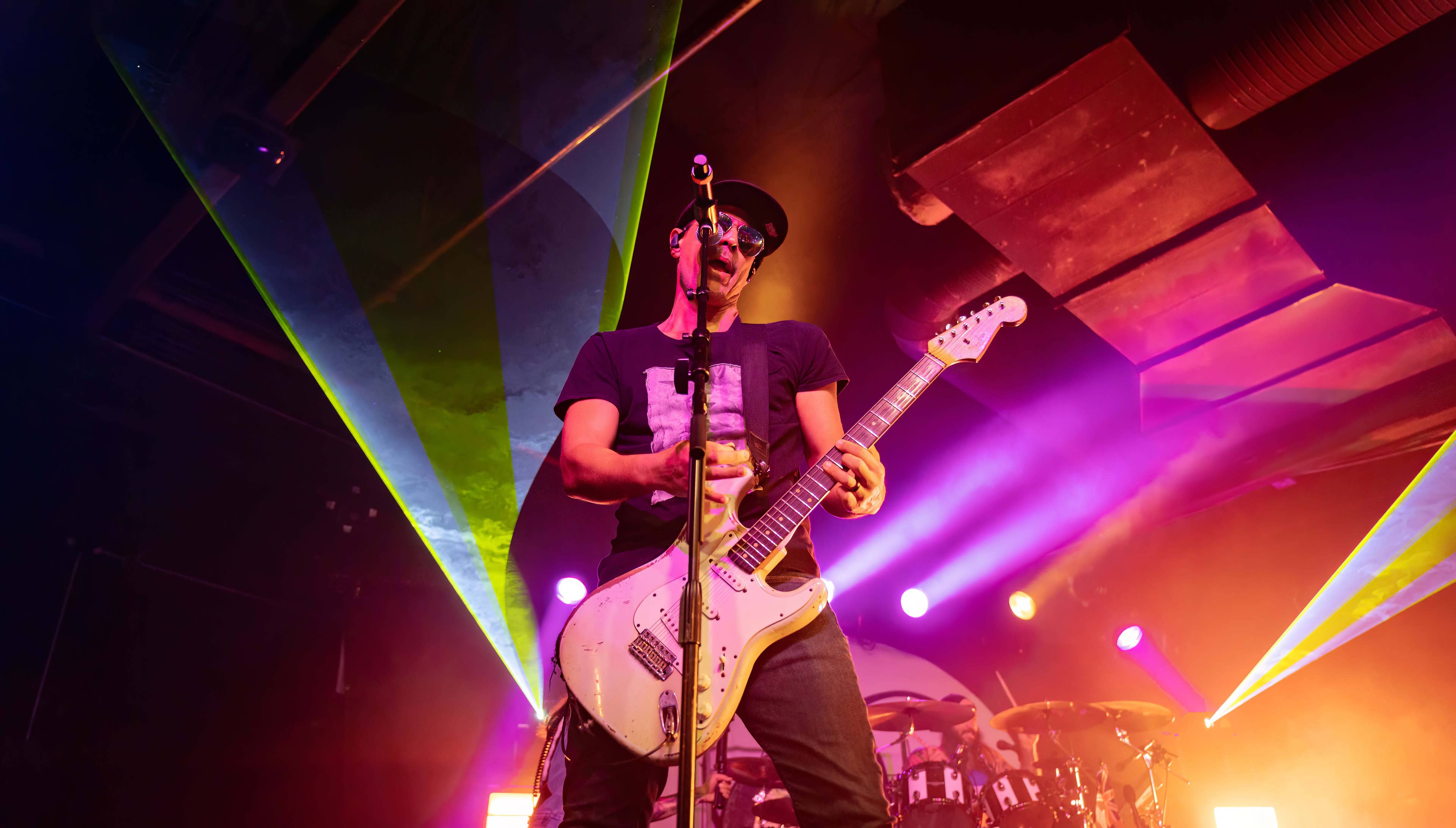 A man singing into a microphone playing the guitar