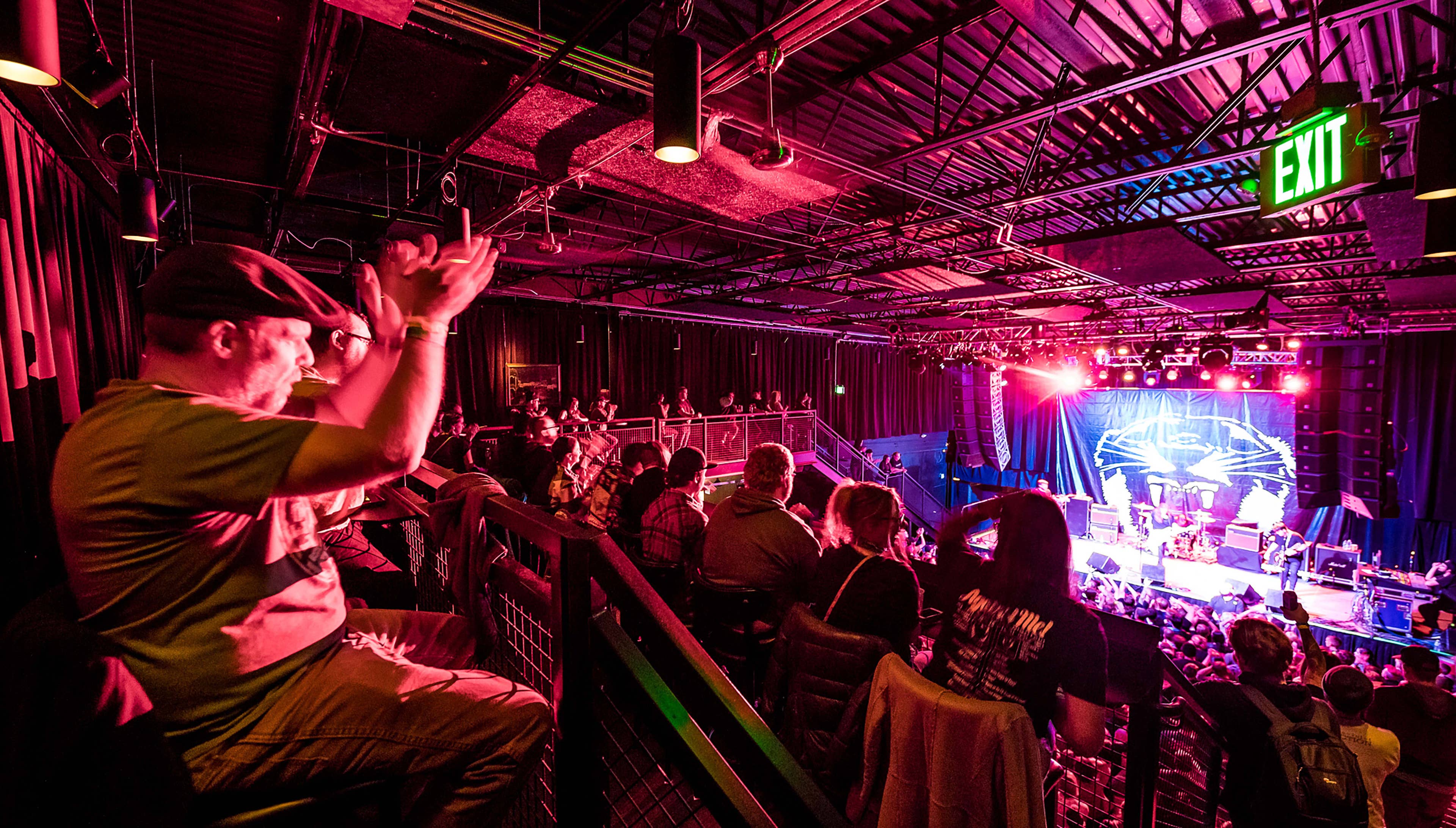 An attendee claps at a show from the balcony